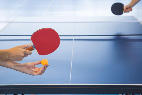 hands holding a rackets and ball and playing on the blue tennis table 480x480